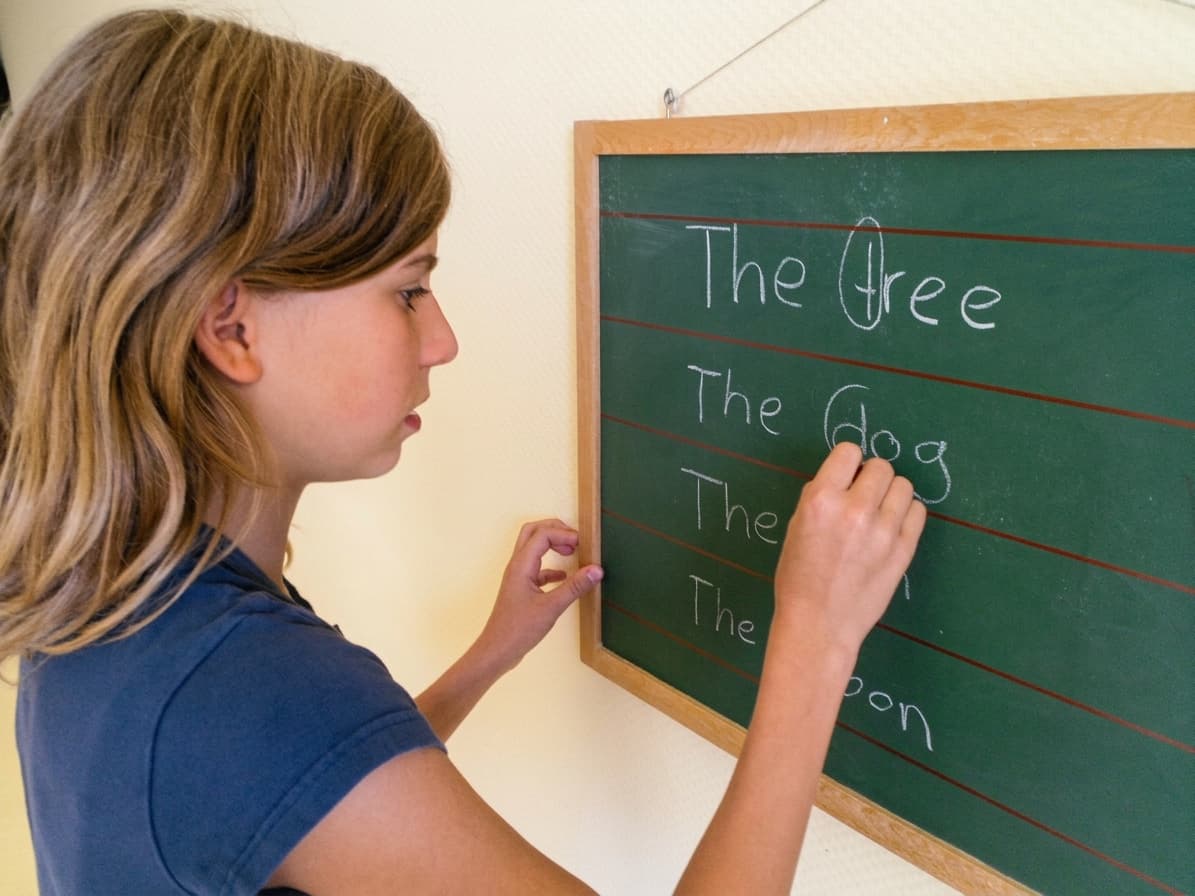 Mädchen schreibt englische Wörter an eine Tafel